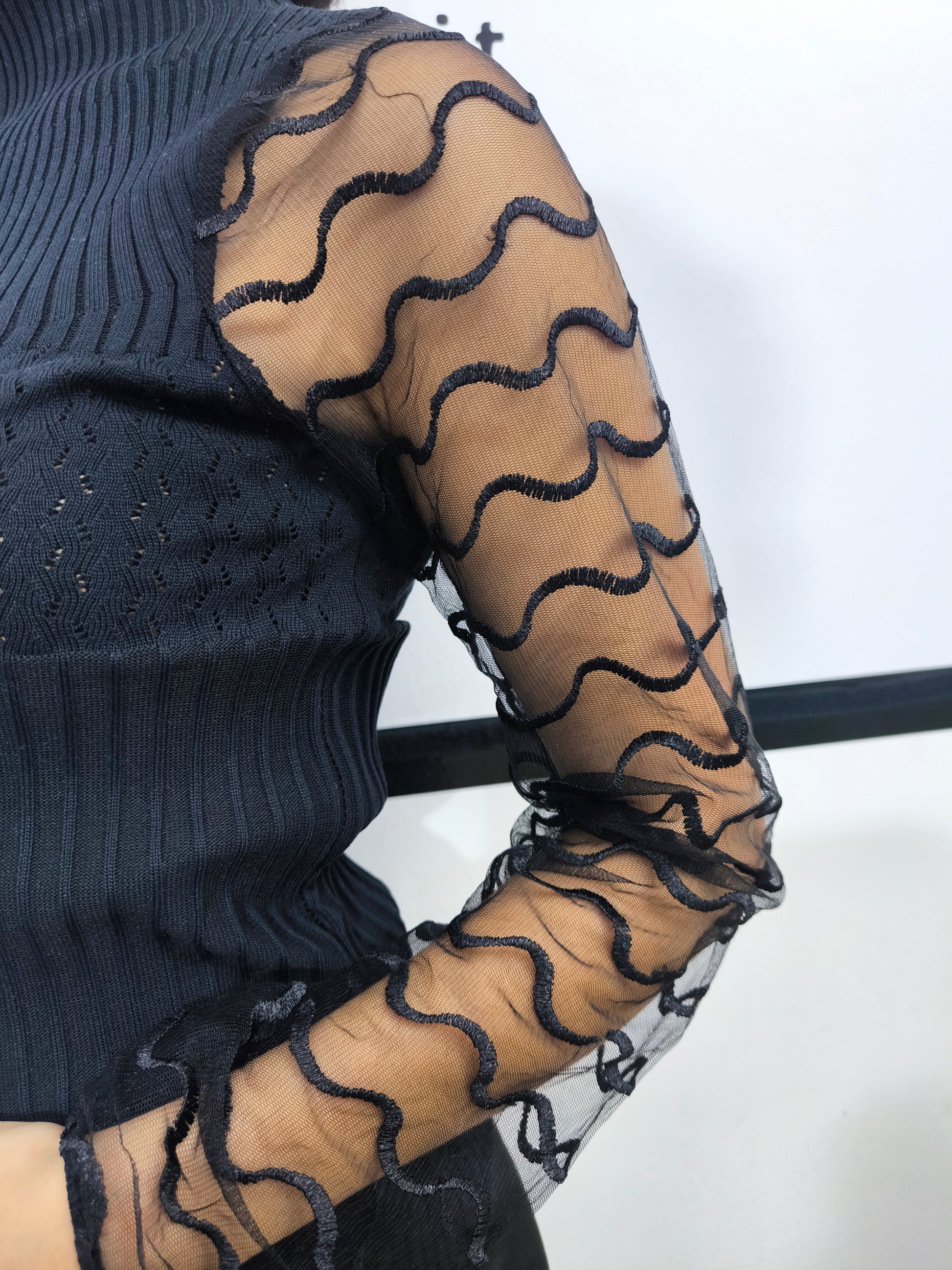 Maglia nera a collo alto con maniche trasparenti in tulle ondulato, abbigliamento elegante donna, perfetto per look casual o formali