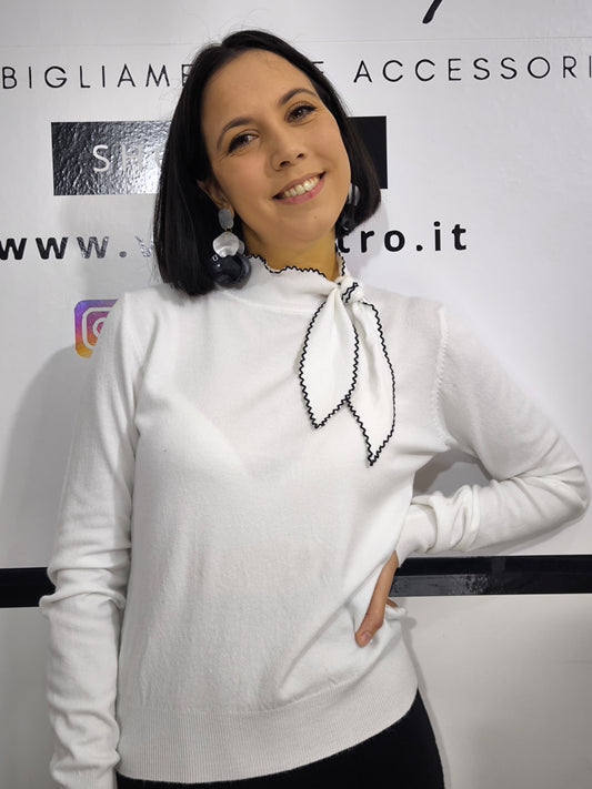 Maglia bianca con fiocco al collo e bordo ricamato in nero, elegante e raffinata.