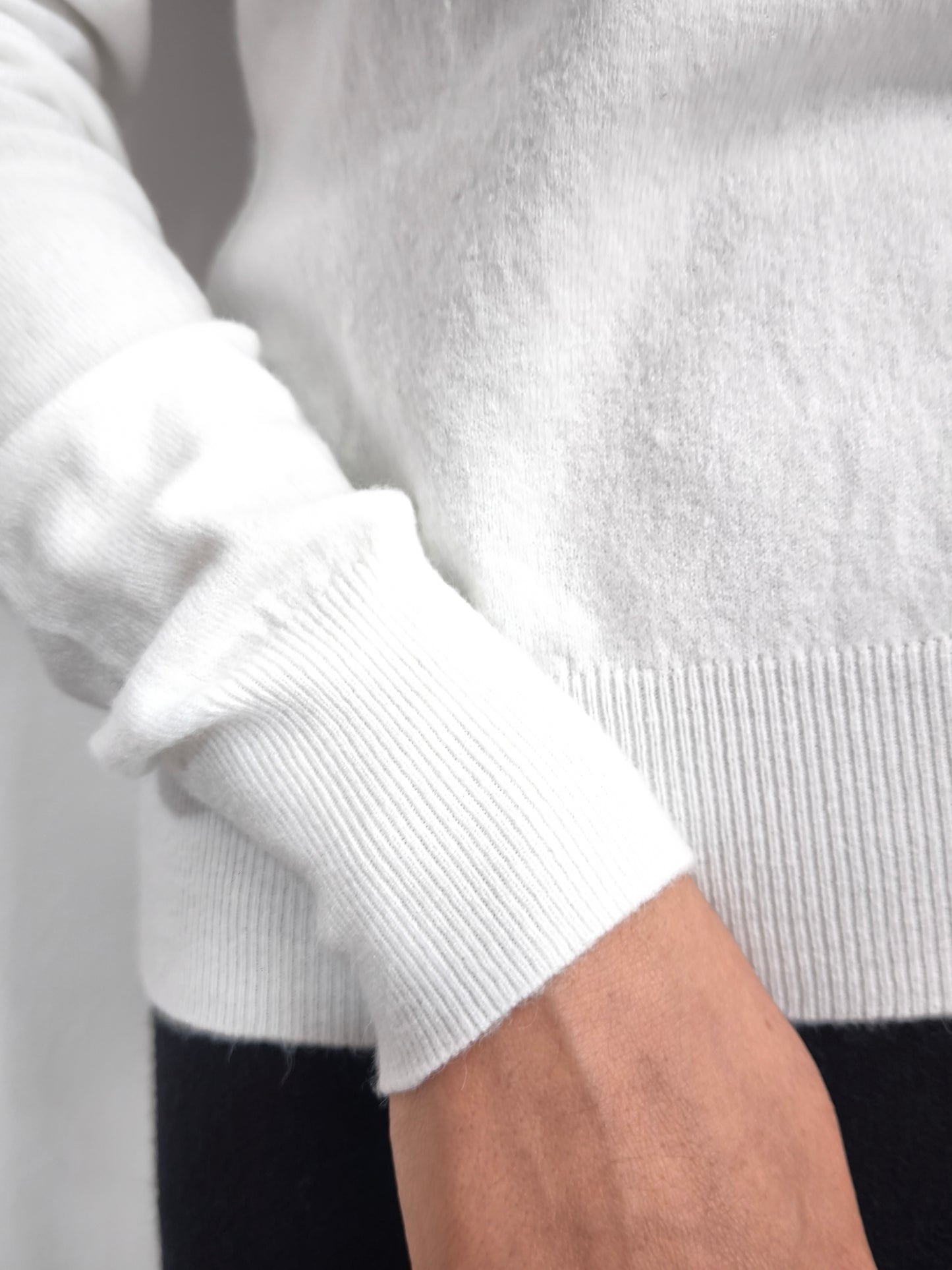 Maglia bianca con fiocco al collo e bordo ricamato in nero, elegante e raffinata.