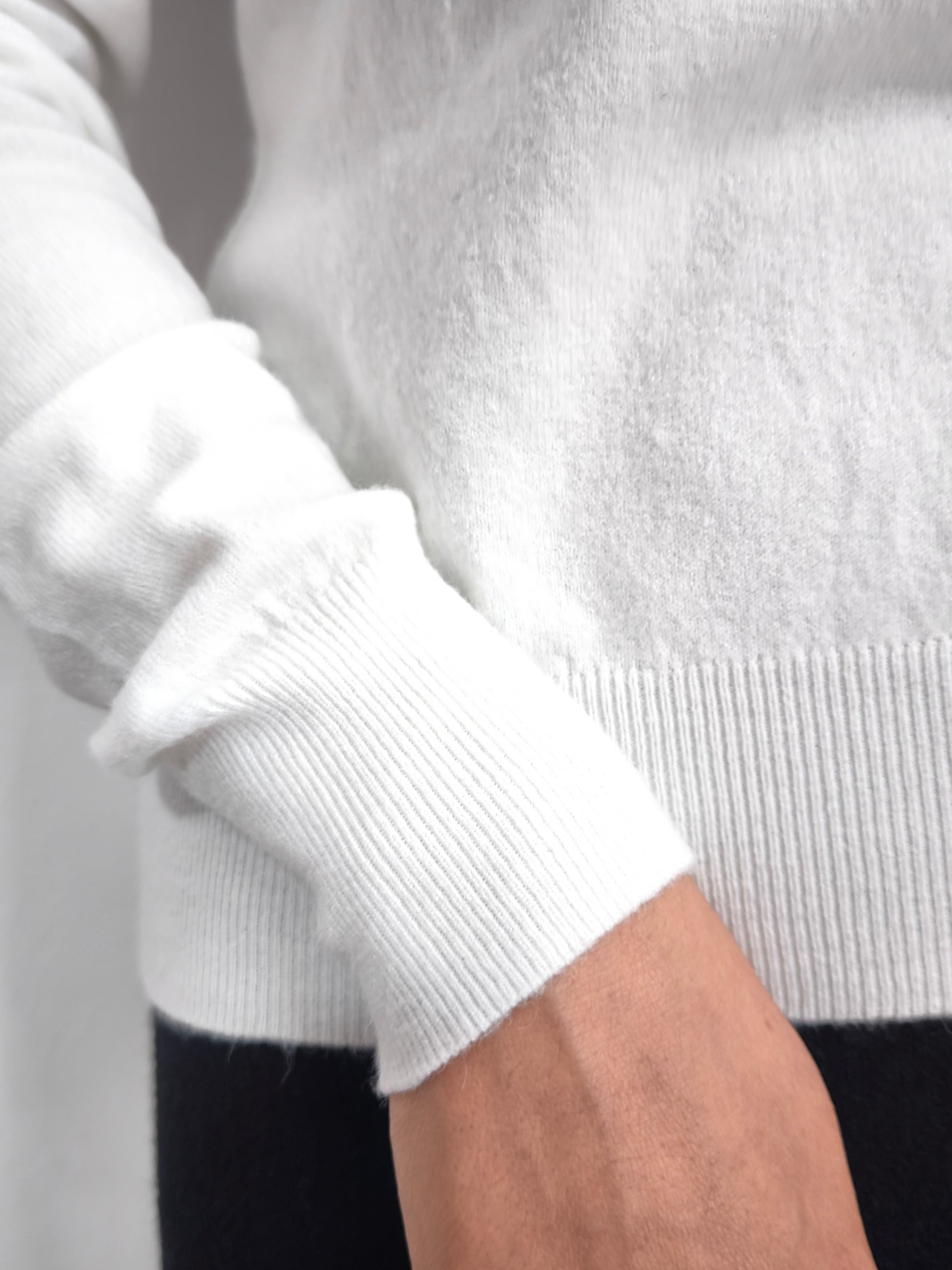 Maglia bianca con fiocco al collo e bordo ricamato in nero, elegante e raffinata.