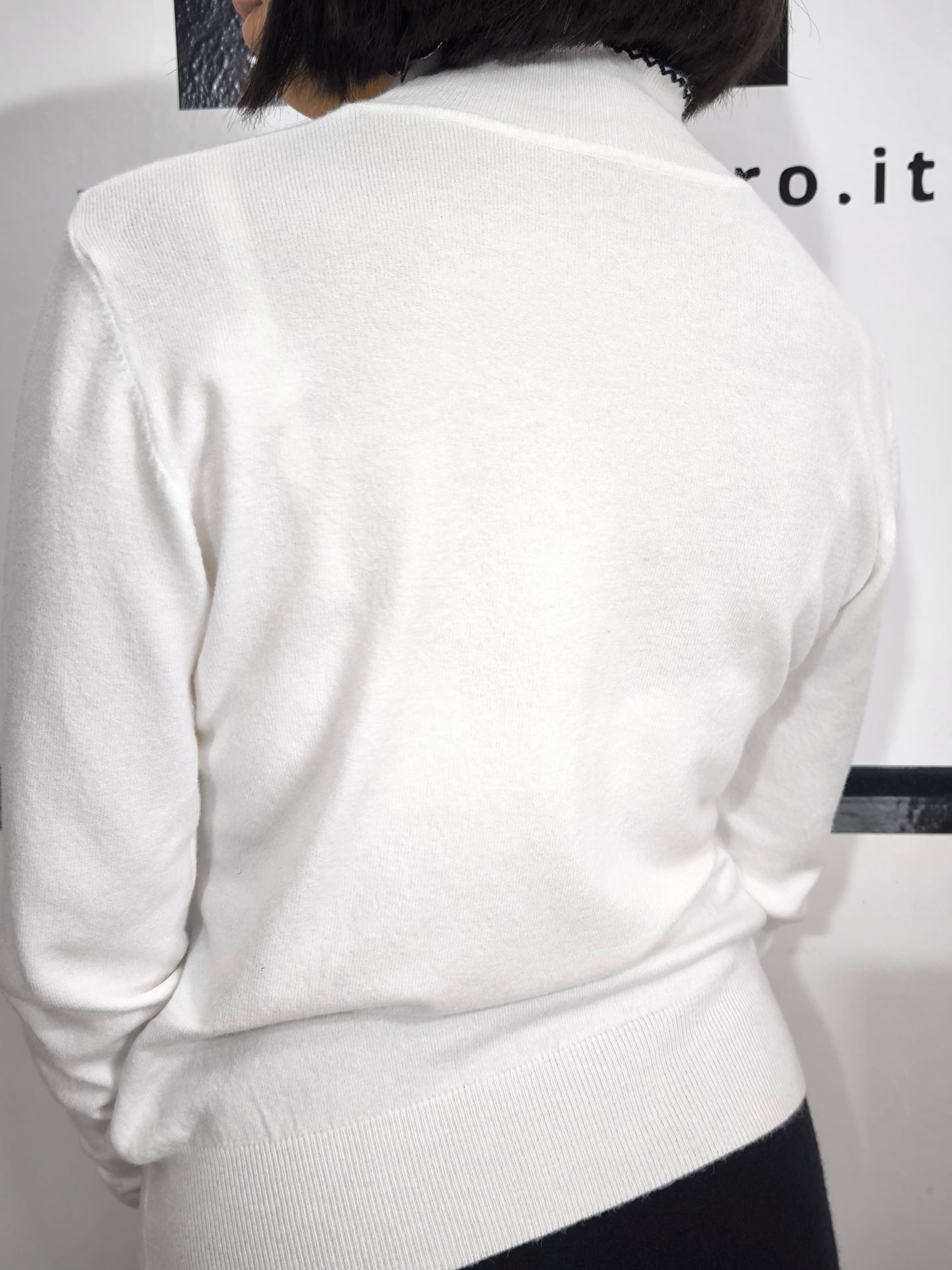 Maglia bianca con fiocco al collo e bordo ricamato in nero, elegante e raffinata.