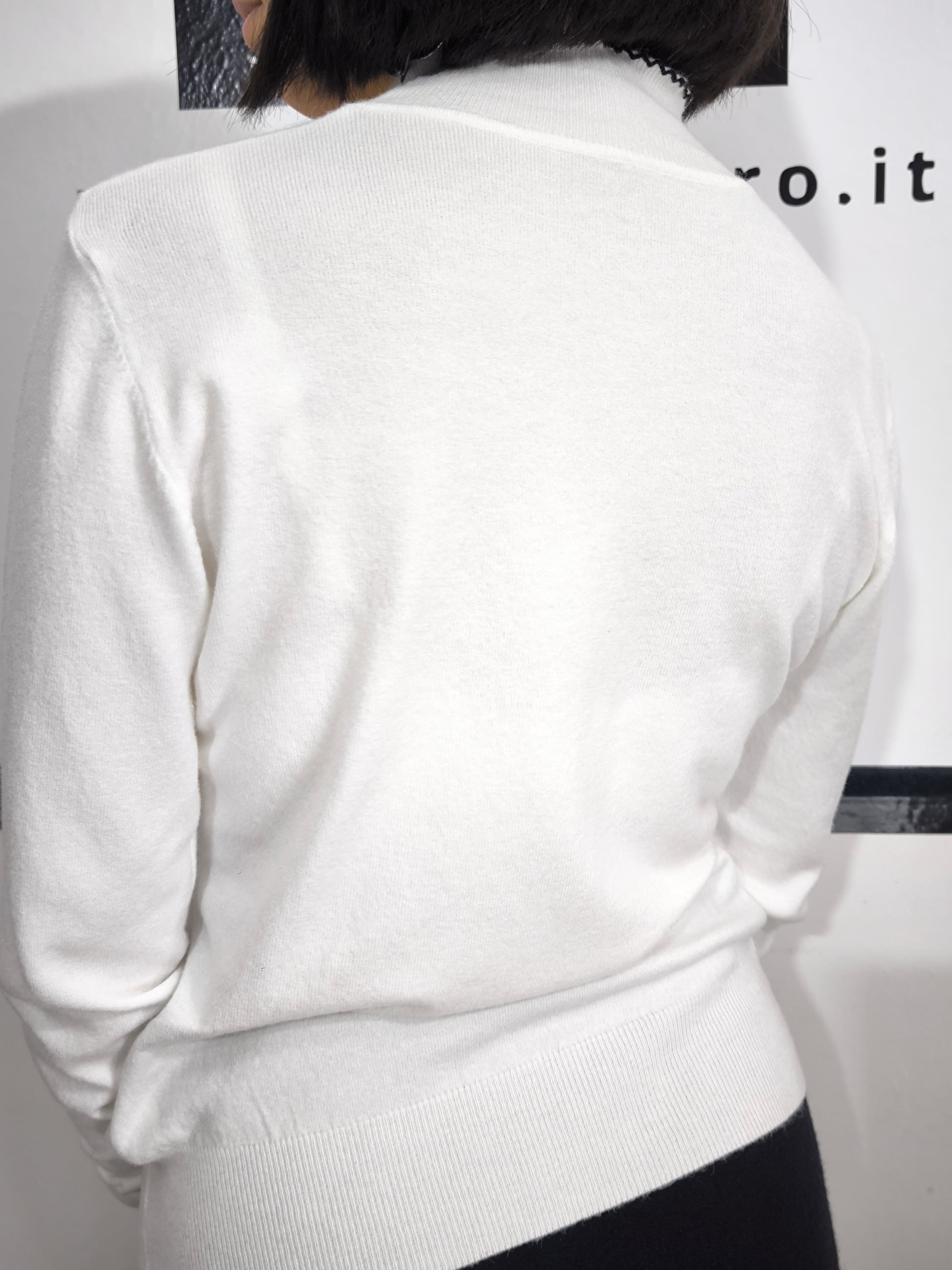 Maglia bianca con fiocco al collo e bordo ricamato in nero, elegante e raffinata.