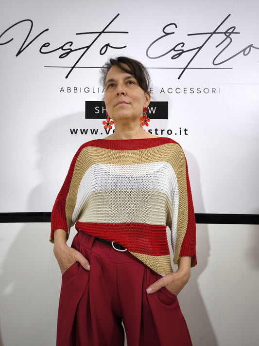 Maglione a righe da donna in maglia larga con colori rosso, beige e bianco, abbinato a pantaloni palazzo per un look casual-chic.