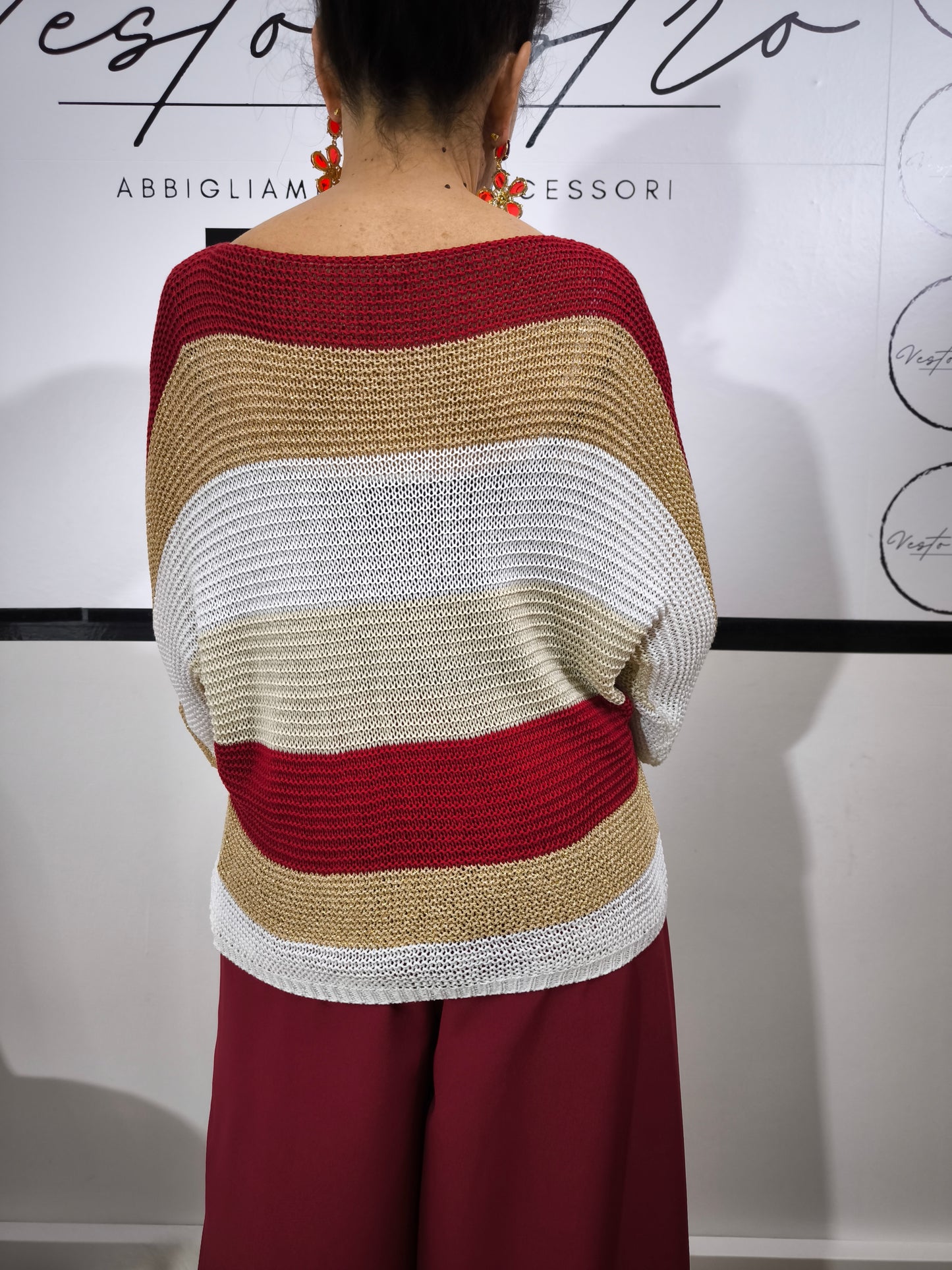 Maglione a righe da donna in maglia larga con colori rosso, beige e bianco, abbinato a pantaloni palazzo per un look casual-chic.