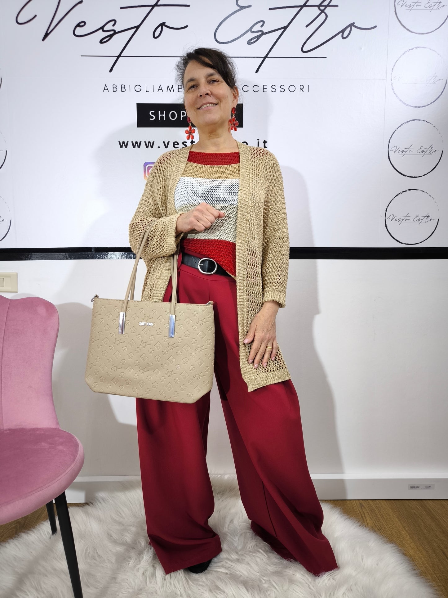 Maglione a righe da donna in maglia larga con colori rosso, beige e bianco, abbinato a pantaloni palazzo per un look casual-chic.