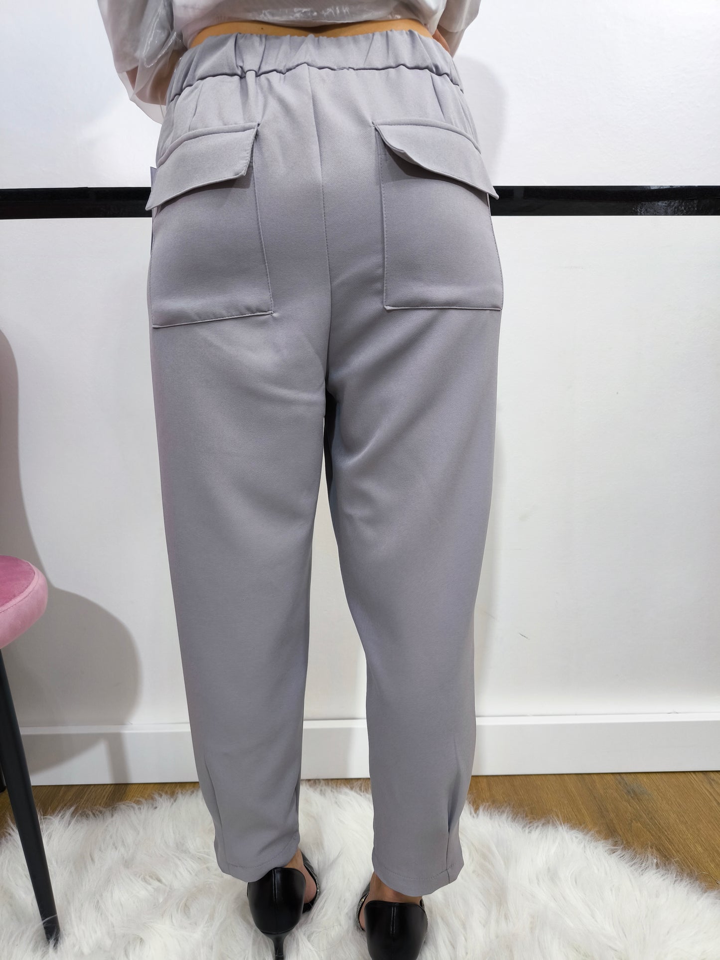 Pantalone grigio con tasche posteriori a patta, vestibilità dritta e chiusura con bottone e cerniera, ideale per un look casual chic o formale.