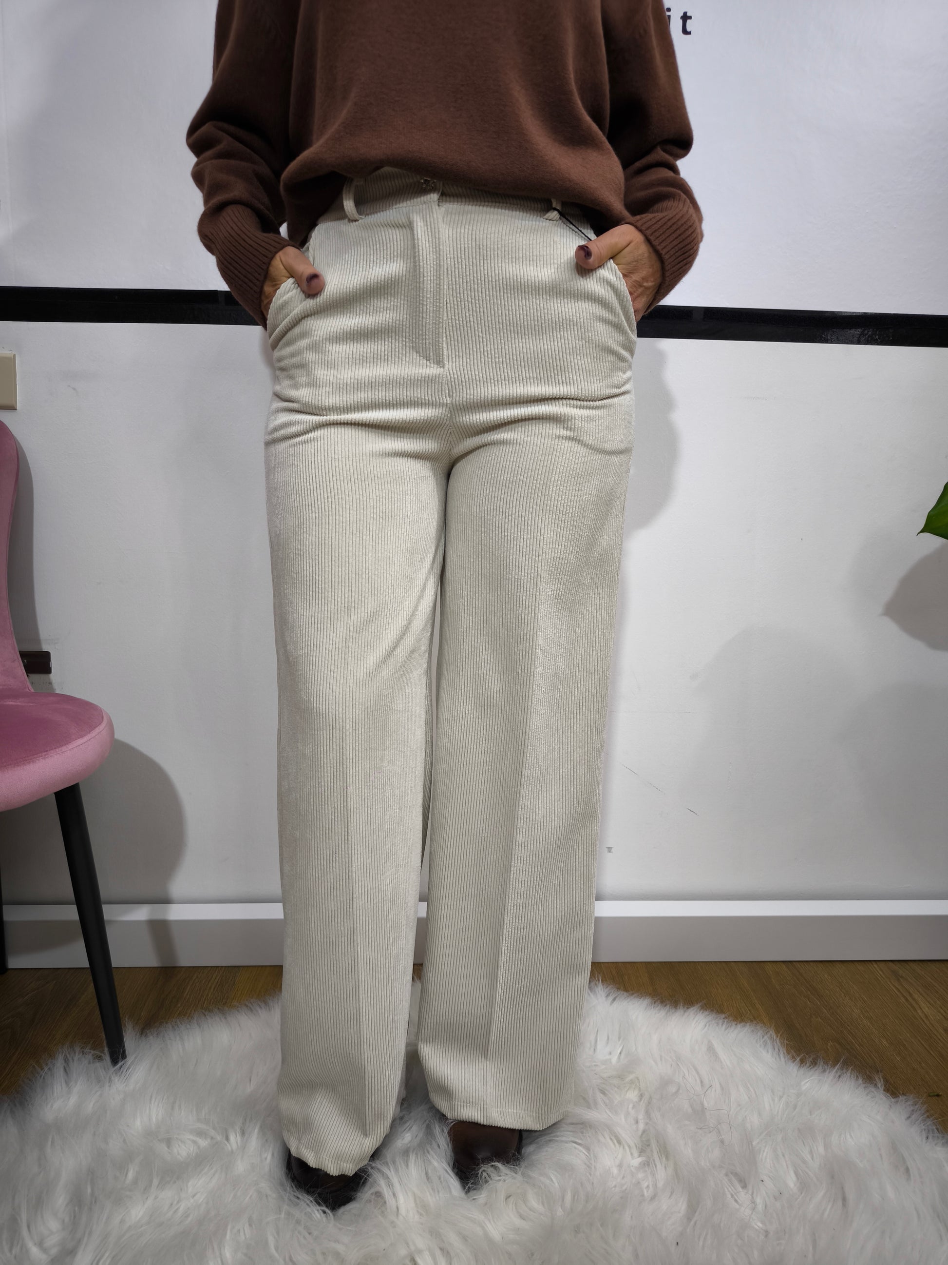 Pantalone in velluto a costine beige con taglio a palazzo indossato da donna con maglione marrone.