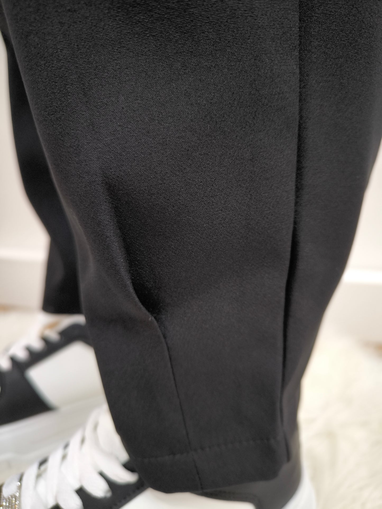 Pantalone nero con tasche posteriori a patta, vestibilità dritta e chiusura con bottone e cerniera, ideale per un look casual chic o formale.