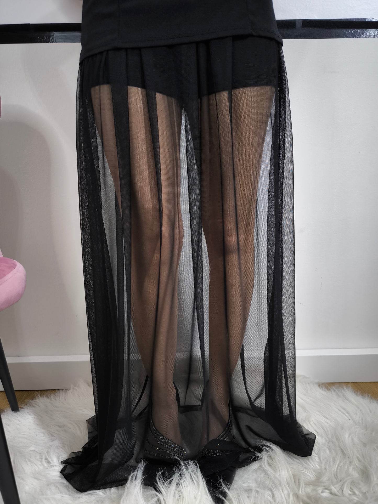Donna indossa una tutina nera senza spalline con gonnellone in tulle cucito in vita e cintura nera inclusa – look elegante.
