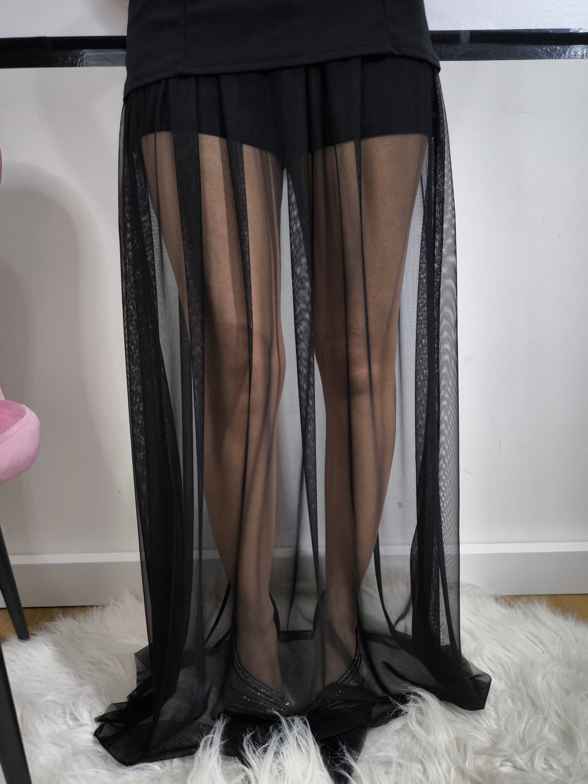 Donna indossa una tutina nera senza spalline con gonnellone in tulle cucito in vita e cintura nera inclusa – look elegante.