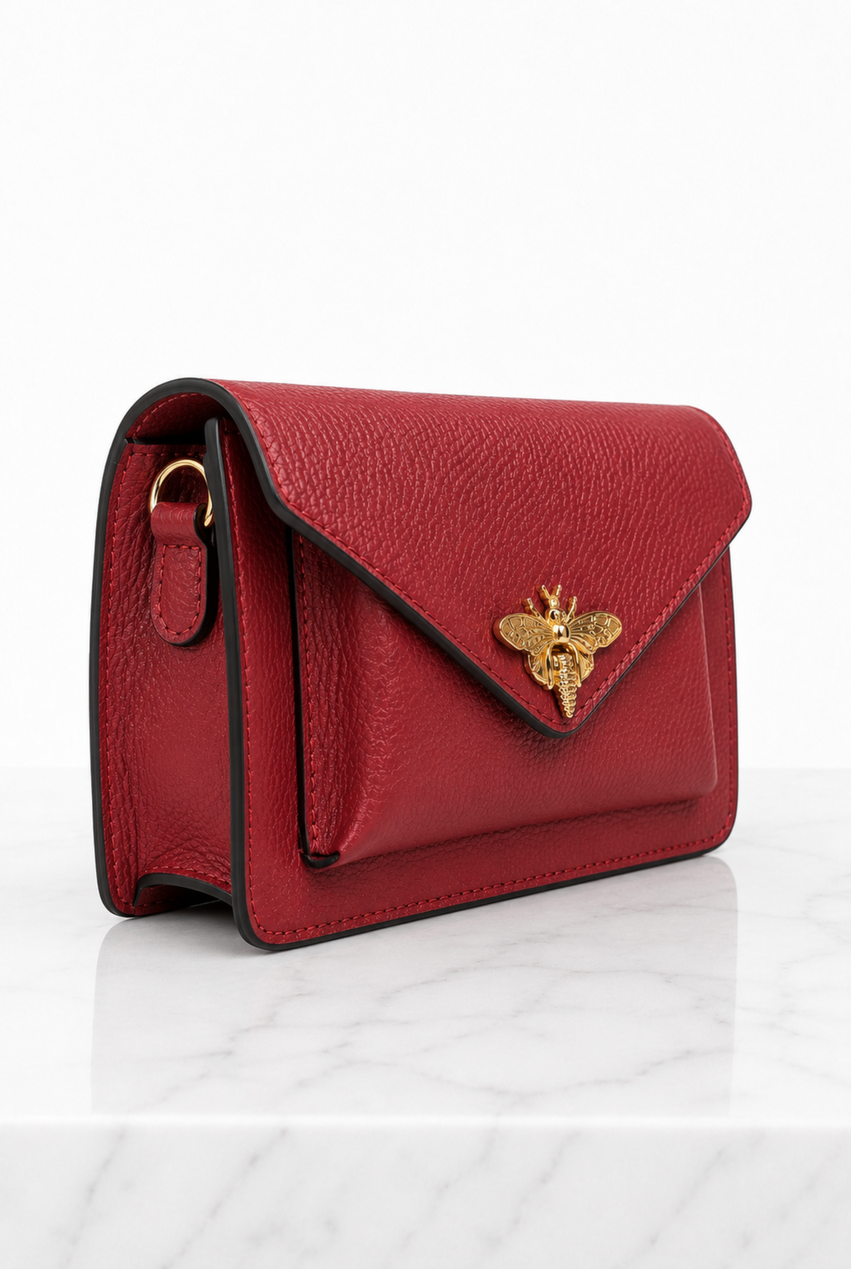 Vista laterale della borsa rossa in vera pelle con profili scuri e accessori dorati