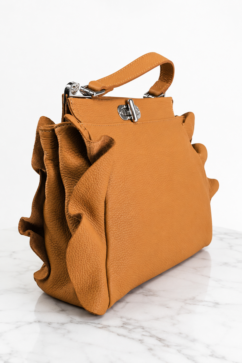 Dettaglio laterale con pieghe della borsa in vera pelle color cammello