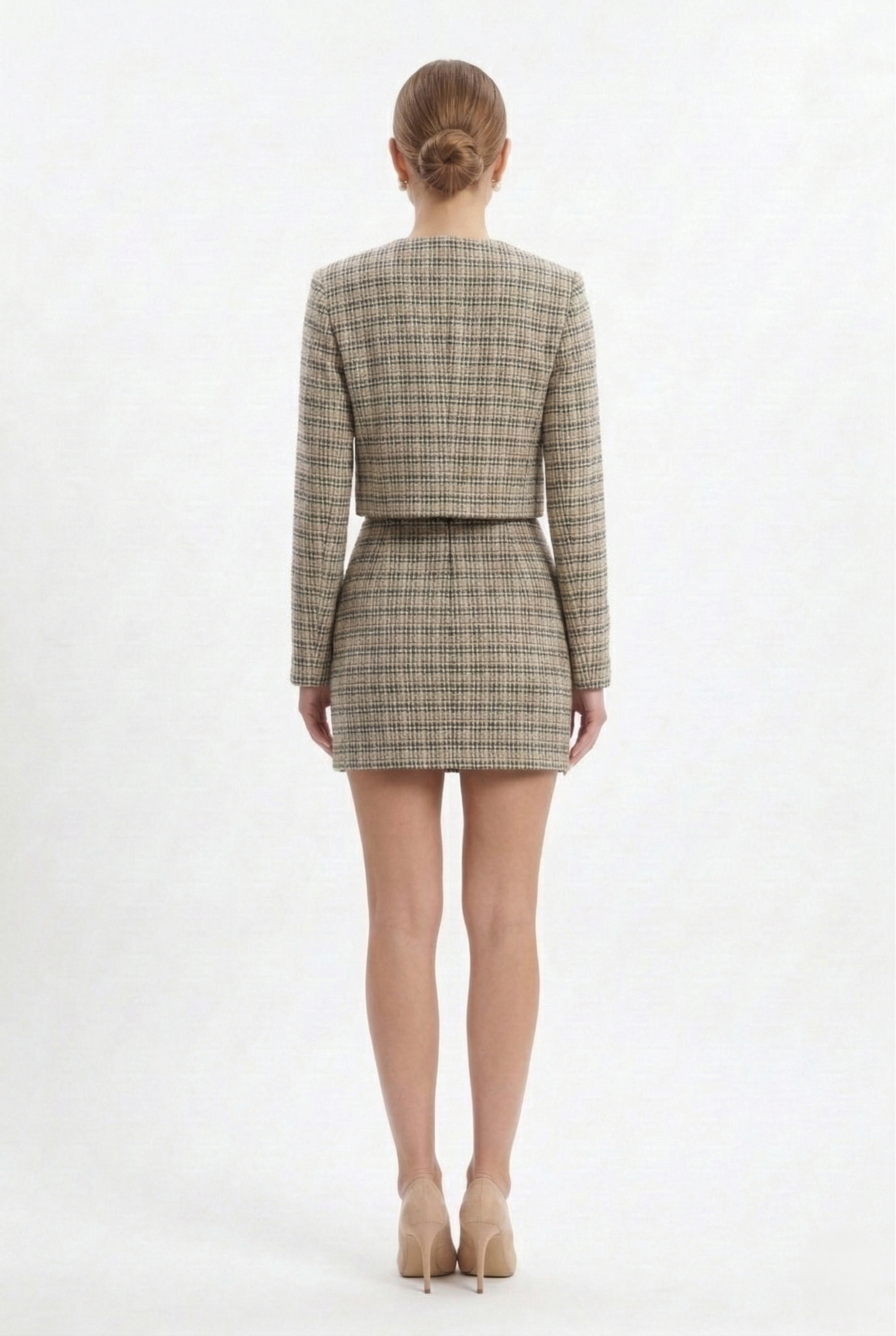 Giacca corta da donna in tweed bianco con bottoni gioiello frontali, parte di completo elegante coordinato.
