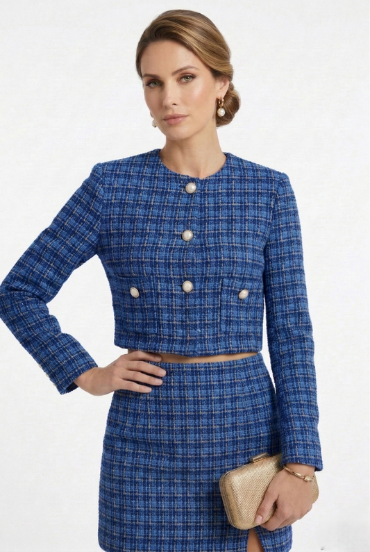 Giacca corta da donna in tweed blu con bottoni gioiello frontali, parte di completo elegante coordinato.