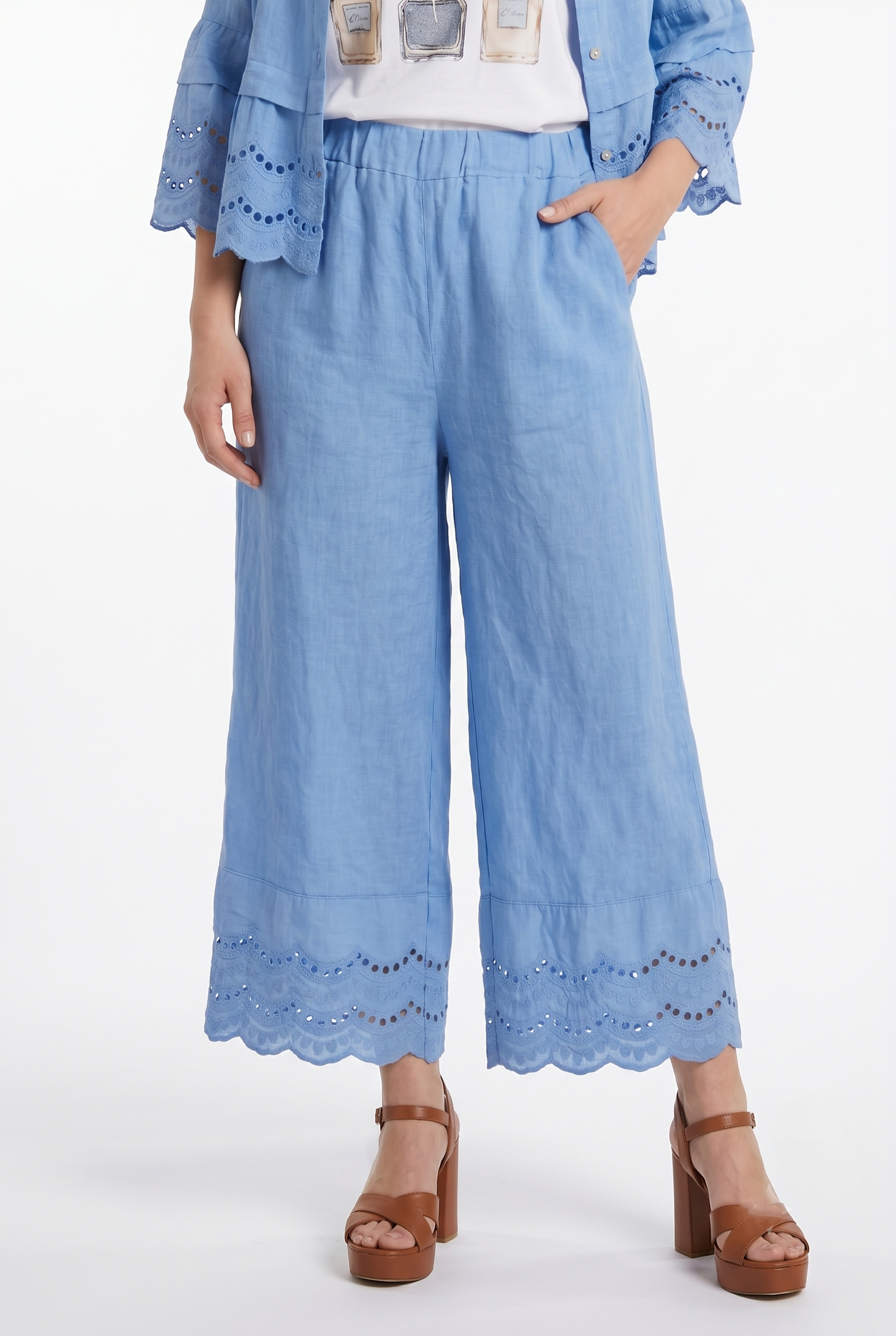 Modella con pantaloni palazzo in puro lino azzurro, gamba larga e ricamo sangallo alla caviglia.