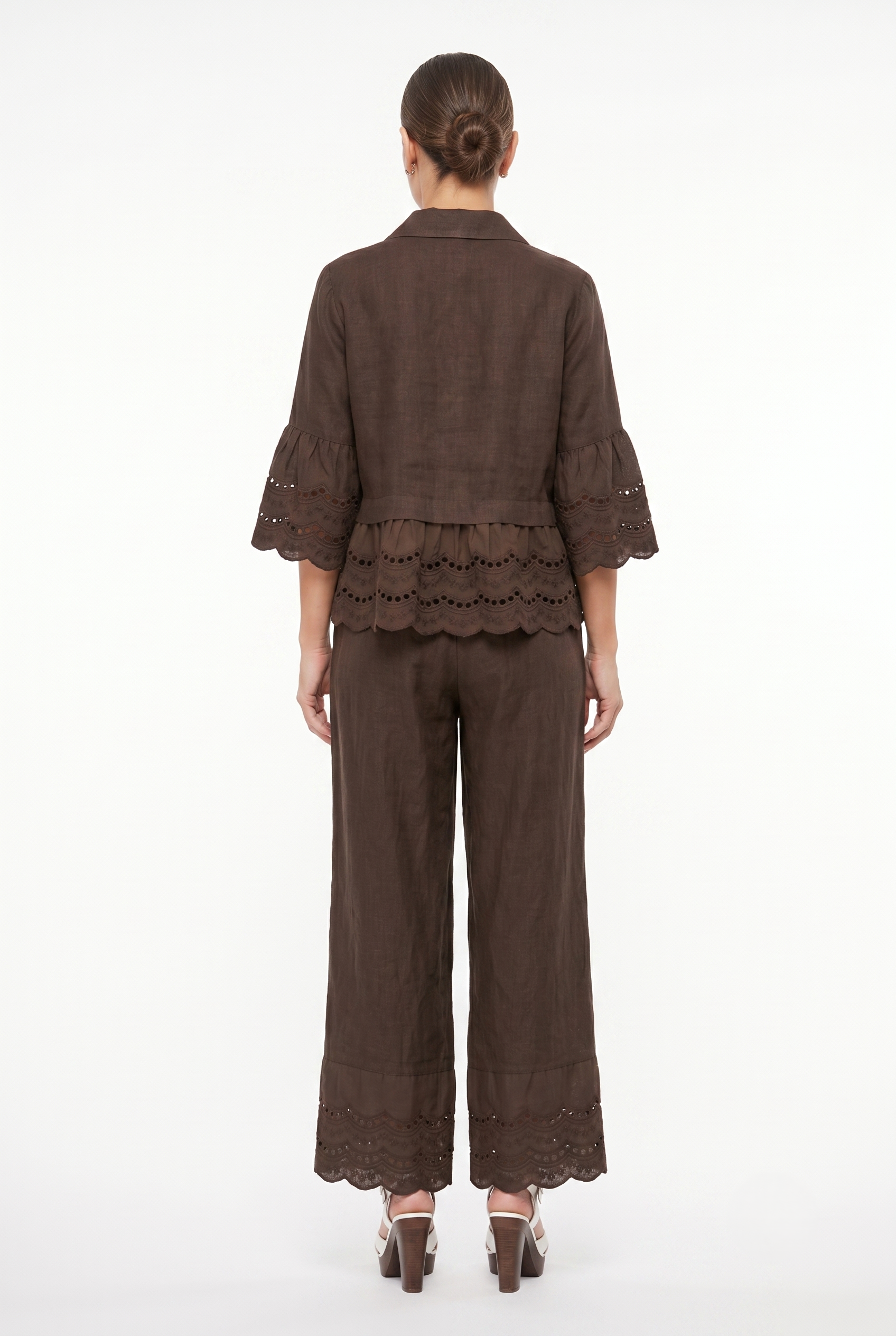 Vista posteriore dei pantaloni palazzo in lino marrone con gamba larga e bordo sangallo alla caviglia.