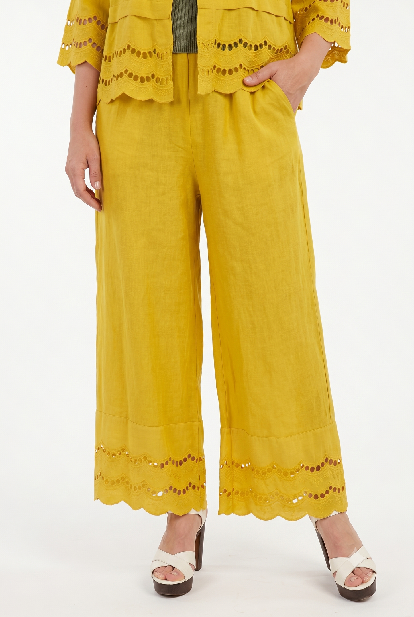 Dettaglio dei pantaloni palazzo donna in lino giallo ocra con vita elasticizzata, tasche e ricamo sangallo.