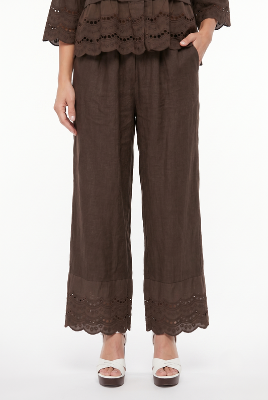 Dettaglio frontale dei pantaloni palazzo donna in puro lino marrone con tasche e ricamo sangallo sul fondo.